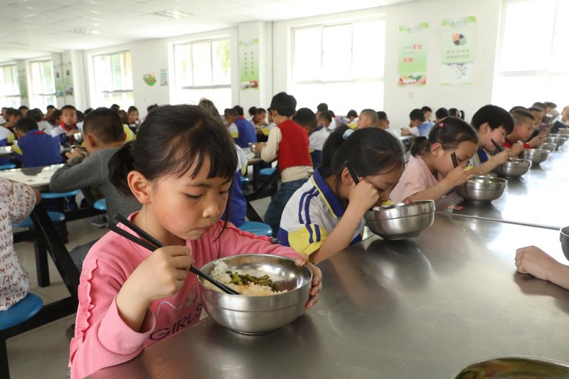小学生们正在学校食堂享用免费营养午餐